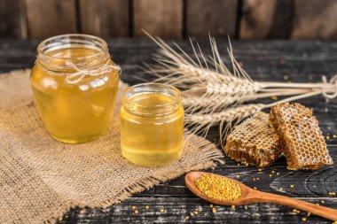 Banka, peteğin ve polen ahşap bir masa üzerinde güzel şeffaf tatlım. Arka plan olarak kullanılabilir