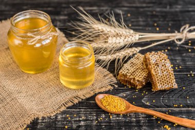 Banka, peteğin ve polen ahşap bir masa üzerinde güzel şeffaf tatlım. Arka plan olarak kullanılabilir