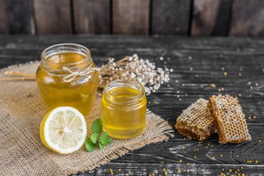 Banka, peteğin ve polen ahşap bir masa üzerinde güzel şeffaf tatlım. Arka plan olarak kullanılabilir