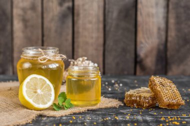 Banka, peteğin ve polen ahşap bir masa üzerinde güzel şeffaf tatlım. Arka plan olarak kullanılabilir