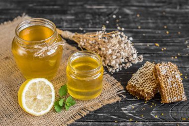 Banka, peteğin ve polen ahşap bir masa üzerinde güzel şeffaf tatlım. Arka plan olarak kullanılabilir