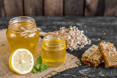 Banka, peteğin ve polen ahşap bir masa üzerinde güzel şeffaf tatlım. Arka plan olarak kullanılabilir