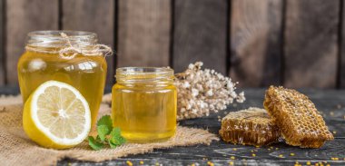 Banka, peteğin ve polen ahşap bir masa üzerinde güzel şeffaf tatlım. Arka plan olarak kullanılabilir