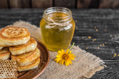 Banka, peteğin ve polen ahşap bir masa üzerinde güzel şeffaf tatlım. Arka plan olarak kullanılabilir