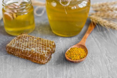 Banka, peteğin ve polen ahşap bir masa üzerinde güzel şeffaf tatlım. Arka plan olarak kullanılabilir