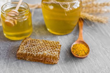 Banka, peteğin ve polen ahşap bir masa üzerinde güzel şeffaf tatlım. Arka plan olarak kullanılabilir