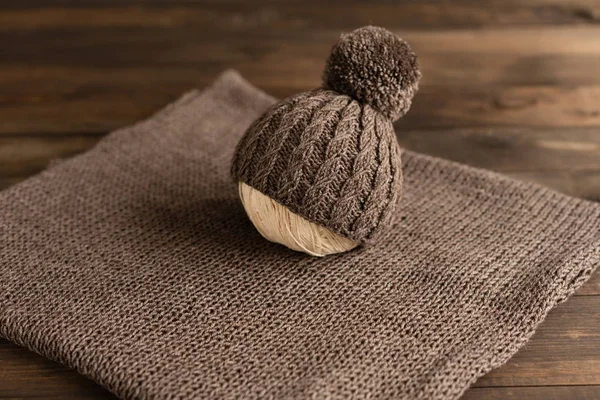 Knitted children\'s cap and cloth on a dark wooden background