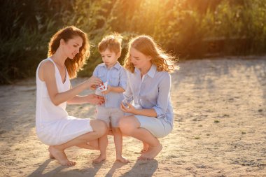 Kardeşi ve kız kardeşi ve annesi deniz sahil sarı kum üzerinde