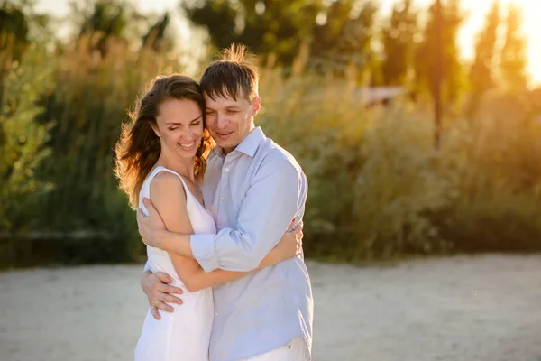 Happy couple with a smile upon the face on summer holiday on the bank of the lake