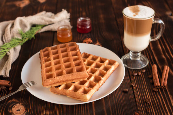 Tasty fresh Vienna wafers, jam and cup of coffee on a dark wooden background