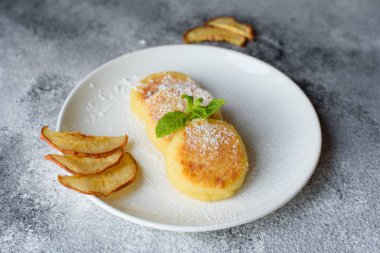 Lezzetli taze peynir krep ile bir bardak süt bir beton zemin üzerine beyaz bir plaka üzerinde. Sağlıklı ve diyet kahvaltı