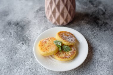 Lezzetli taze peynir krep ile bir bardak süt bir beton zemin üzerine beyaz bir plaka üzerinde. Sağlıklı ve diyet kahvaltı