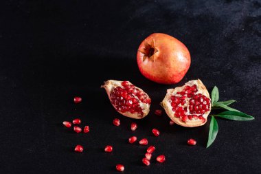 Koyu arkaplanda kırmızı nar suyu. Koyu arkaplanda yaprakları olan olgun bir nar.