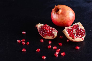 Koyu arkaplanda kırmızı nar suyu. Koyu arkaplanda yaprakları olan olgun bir nar.