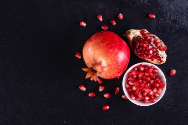 Koyu arkaplanda kırmızı nar suyu. Koyu arkaplanda yaprakları olan olgun bir nar.