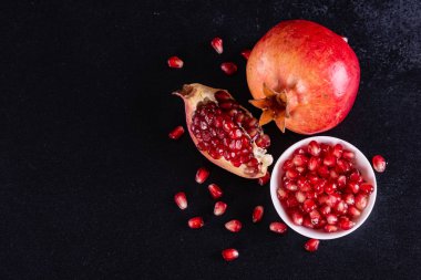 Koyu arkaplanda kırmızı nar suyu. Koyu arkaplanda yaprakları olan olgun bir nar.