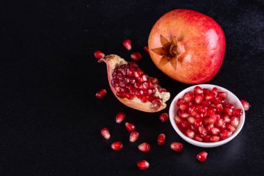 Koyu arkaplanda kırmızı nar suyu. Koyu arkaplanda yaprakları olan olgun bir nar.