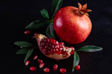 Koyu arkaplanda kırmızı nar suyu. Koyu arkaplanda yaprakları olan olgun bir nar.