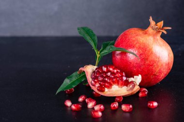 Koyu arkaplanda kırmızı nar suyu. Koyu arkaplanda yaprakları olan olgun bir nar.