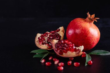 Koyu arkaplanda kırmızı nar suyu. Koyu arkaplanda yaprakları olan olgun bir nar.