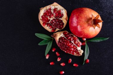 Koyu arkaplanda kırmızı nar suyu. Koyu arkaplanda yaprakları olan olgun bir nar.