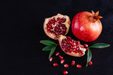 Koyu arkaplanda kırmızı nar suyu. Koyu arkaplanda yaprakları olan olgun bir nar.