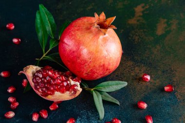Koyu arkaplanda kırmızı nar suyu. Koyu arkaplanda yaprakları olan olgun bir nar.