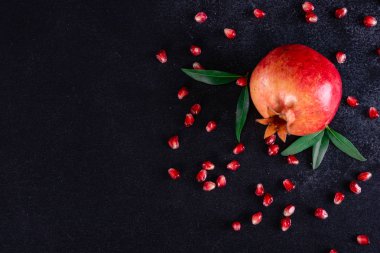 Koyu arkaplanda kırmızı nar suyu. Koyu arkaplanda yaprakları olan olgun bir nar.