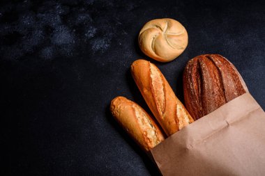 Tahıllar ve koyu bir arka plan karşı buğday konileri ile taze kokulu ekmek. Ahşap masa arka plan üzerinde pişmiş ekmek çeşitleri. Masada taze kokulu ekmek var. Gıda konsepti. 