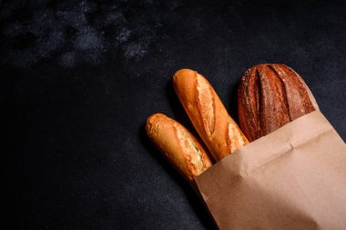 Tahıllar ve koyu bir arka plan karşı buğday konileri ile taze kokulu ekmek. Ahşap masa arka plan üzerinde pişmiş ekmek çeşitleri. Masada taze kokulu ekmek var. Gıda konsepti. 