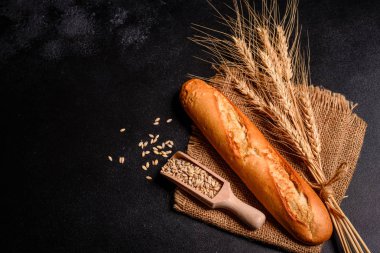 Tahıllar ve koyu bir arka plan karşı buğday konileri ile taze kokulu ekmek. Ahşap masa arka plan üzerinde pişmiş ekmek çeşitleri. Masada taze kokulu ekmek var. Gıda konsepti. 