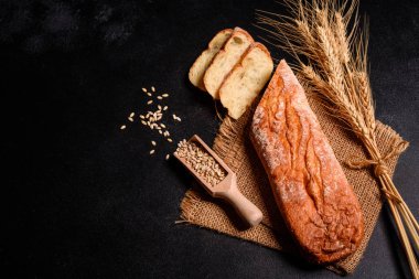 Tahıllar ve koyu bir arka plan karşı buğday konileri ile taze kokulu ekmek. Ahşap masa arka plan üzerinde pişmiş ekmek çeşitleri. Masada taze kokulu ekmek var. Gıda konsepti. 