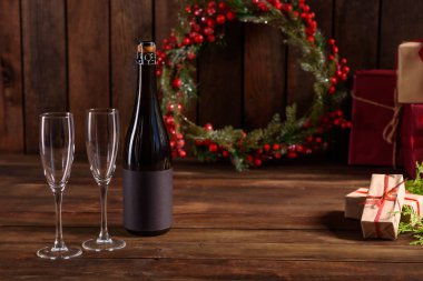 Noel tatili masası, bardaklar ve bir şişe şampanya. Yeni yıl arifesinde, hazırlık ve ahşap bir tatil masası döşeme