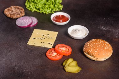 Koyu arka planda burger malzemeleri. Üstte görüntü
