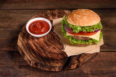 Sığır eti, domates, peynir, salatalık ve marul ile lezzetli ızgara ev yapımı burger. Lezzetli ızgara burgerler. Ahşap masada zanaat sığır burger ve patates kızartması