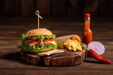 Sığır eti, domates, peynir, salatalık ve marul ile lezzetli ızgara ev yapımı burger. Lezzetli ızgara burgerler. Ahşap masada zanaat sığır burger ve patates kızartması