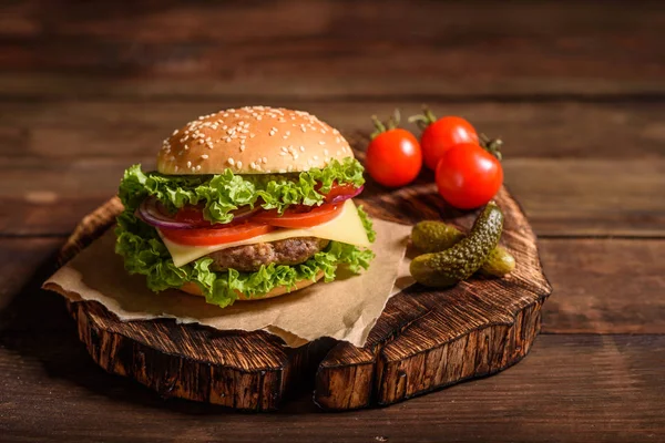 Tasty grilled homemade burger with beef, tomato, cheese, cucumber and lettuce. Delicious grilled burgers. Craft beef burger and french fries on wooden table