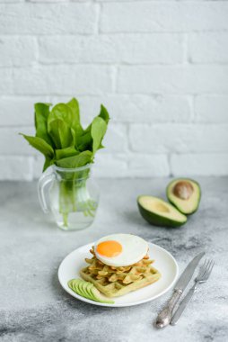 Taze lezzetli ve besleyici kahvaltı ıspanaklı waffle, kızarmış yumurta ve avokado parçaları.