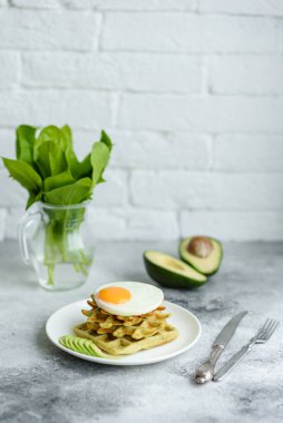 Taze lezzetli ve besleyici kahvaltı ıspanaklı waffle, kızarmış yumurta ve avokado parçaları.