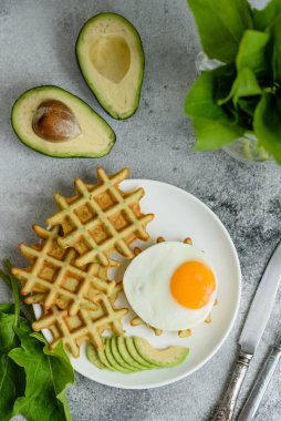 Taze lezzetli ve besleyici kahvaltı ıspanaklı waffle, kızarmış yumurta ve avokado parçaları.