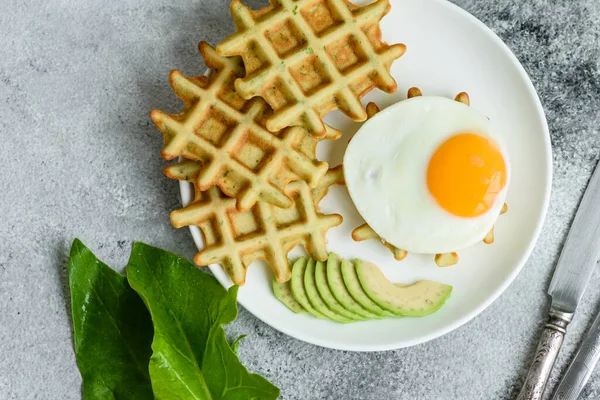 Taze lezzetli ve besleyici kahvaltı ıspanaklı waffle, kızarmış yumurta ve avokado parçaları.