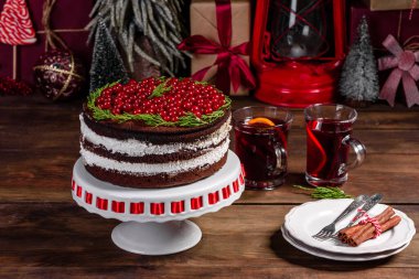 Beautiful delicious cake with bright red berries on the Christmas table with fragrant mulled wine with spices clipart