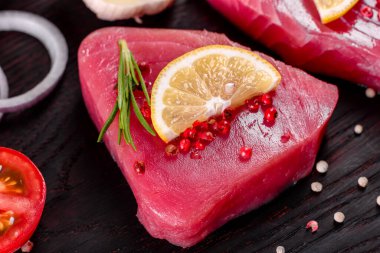 Siyah arka planda baharatlı ve şifalı ton balığı bifteği. Ton balığı pişirmeye hazırlanıyor.