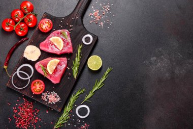 Siyah arka planda baharatlı ve şifalı ton balığı bifteği. Ton balığı pişirmeye hazırlanıyor.