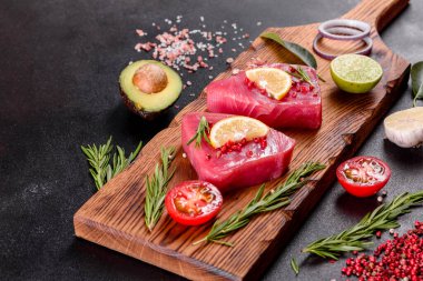 Siyah arka planda baharatlı ve şifalı ton balığı bifteği. Ton balığı pişirmeye hazırlanıyor.