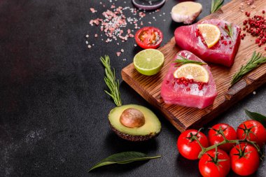 Siyah arka planda baharatlı ve şifalı ton balığı bifteği. Ton balığı pişirmeye hazırlanıyor.