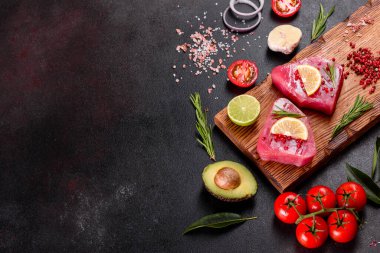 Siyah arka planda baharatlı ve şifalı ton balığı bifteği. Ton balığı pişirmeye hazırlanıyor.