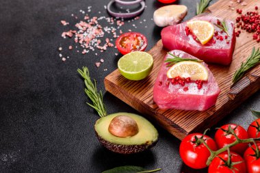 Siyah arka planda baharatlı ve şifalı ton balığı bifteği. Ton balığı pişirmeye hazırlanıyor.