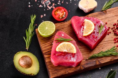 Siyah arka planda baharatlı ve şifalı ton balığı bifteği. Ton balığı pişirmeye hazırlanıyor.