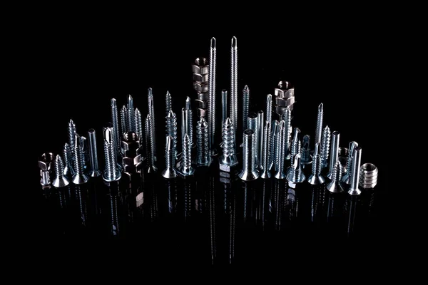 A fantastic city made of bolts, nuts, screws and self-cuts on a black background with reflection. Iron city